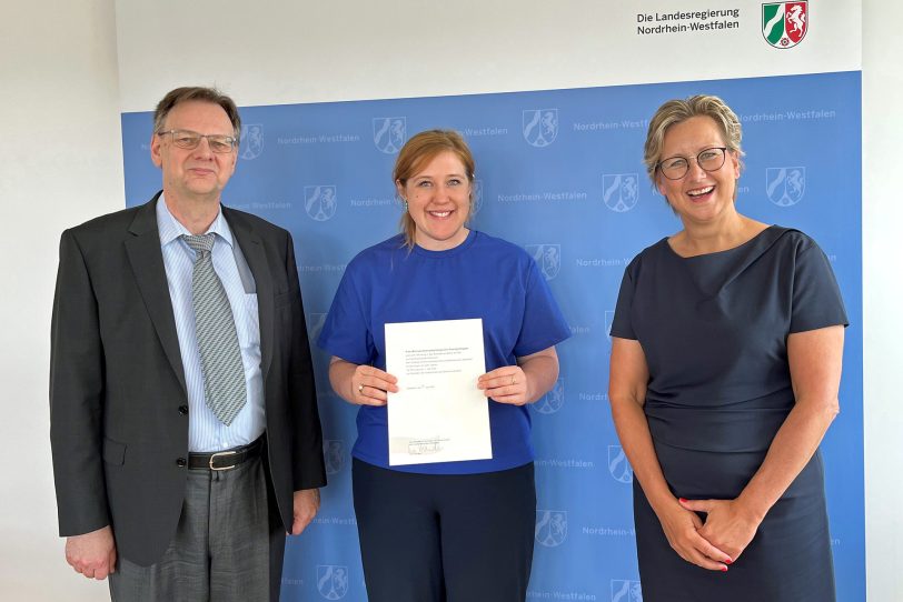 Mit den Ernennungsurkunden, ausgehändigt durch Ministerialdirektor Ralf Thönnissen (l.) vom Ministerium für Kultur und Wissenschaft in NRW, haben Prof. Dr. Tamara Appel (r.) und Svenja Stepper (M.) auch formal ihre Arbeit aufgenommen.
