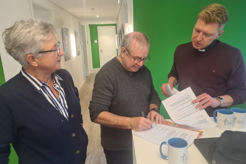 Ein Kirchenfenster für Joachim Król: Gundula Kappen vom Kirchenvorstand, Joachim Król und Pfarrer Dr. Nils Petrat bei der Vertragsunterzeichnung.