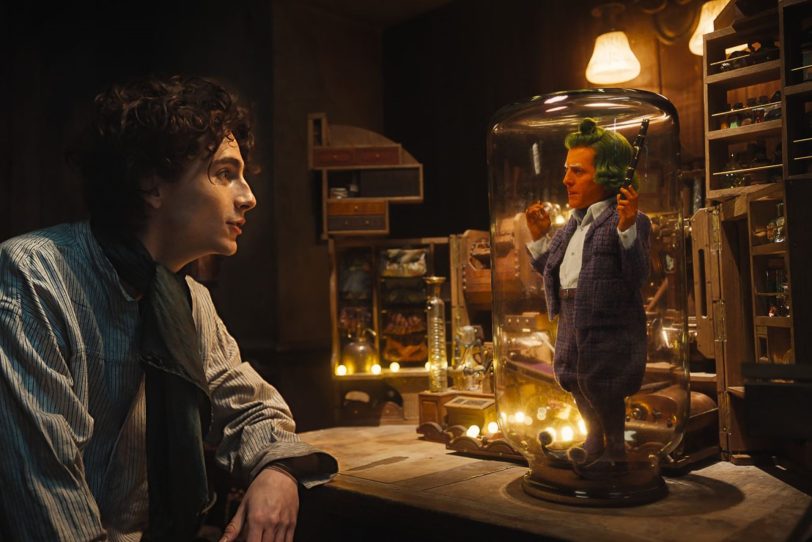Der Oompa-Loompa-Wichtel Lofty (Hugh Grant, r.) ist Willy Wonka (Timothée Chalamet) in die Falle gegangen, kommt aber bald ganz groß ‘raus.