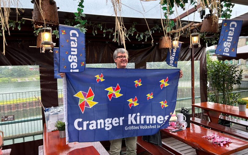 Alexander Christian vom Stadtmarketing präsentiert die großen und kleinen Fahnen für die Cranger Kirmes 2024.