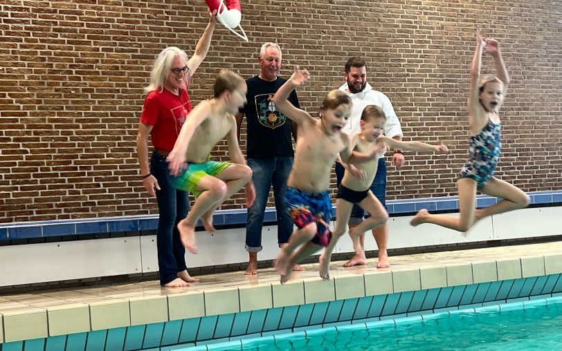 Die Kinder springen mit Freude ins Wasser: Dahinter freuen sich mit ihnen (v.li.) Horst Schröder (Mondritter), Frank Tocholski (Mondritter) und Moritz Trepper (Filialleiter Herne Sparda-Bank West).