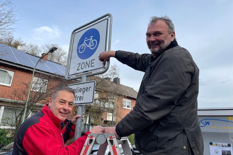 Die letzten Handgriffe am Verkehrsschild von (li.) Roberto Gentilini, Vorsitzender des Ausschusses für Digitalisierung, Infrastruktur und Mobilität, und Stadtrat Karlheinz Friedrichs.