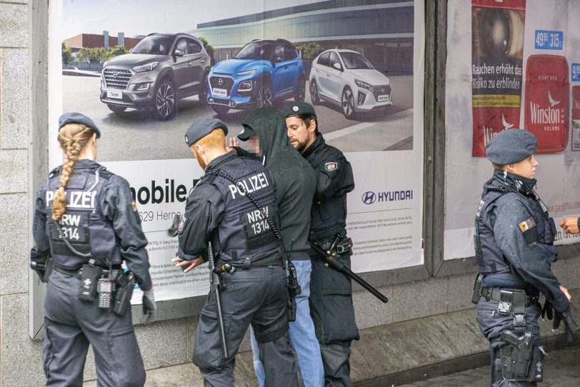Am Rande des 'Spaziergangs besorgter Bürger' durchsucht die Polizei einen Teilnehmer.