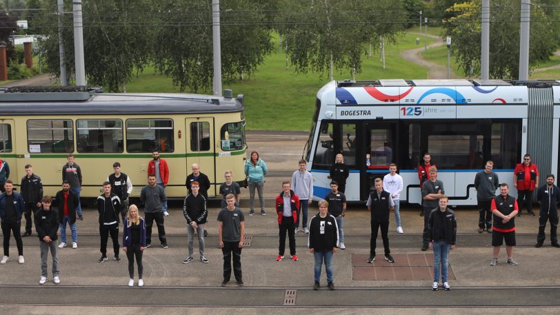Ein Teil der neuen Azubis des Bogestra-Jubiläumsjahrs 2021 vor einer Variobahn (re.) und einer historischen Straßenbahn. Aufgrund der Breite des Bildes im Original sind nicht alle Azubis abgebildet.