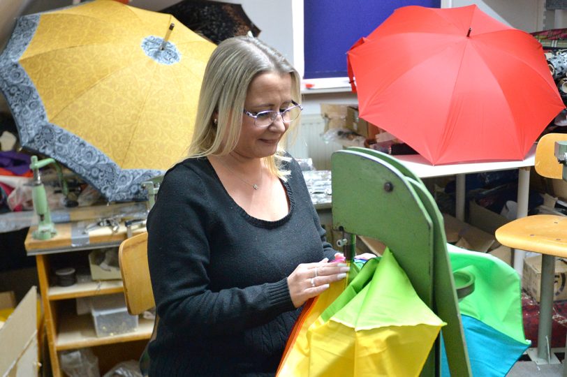 Schirmmacherin Jenny Kossuch an der Maschine, die die Krone in den Stoff stanzt.