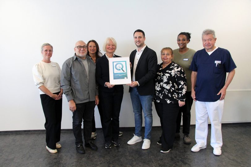 Angelika Burrichter, Leiterin des Gesundheitsamtes Herne, übergibt das MRE-Hygiene-Siegel an René Vidic, Klinikmanager des EvK Herne. Begleitet wurde die offizielle Verleihung von Vertreterinnen und Vertretern des Krankenhauses und des amtsärztlichen Dienstes.