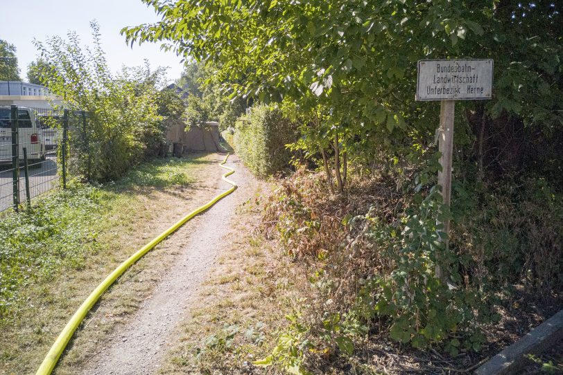 Von der Straße aus führt ein schmaler Weg zu der Kleingartenparzelle am Bahndamm.