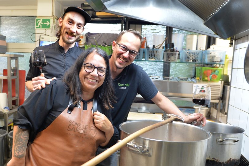 Sardischer Abend im Ollis: Zwei Köche, v.l. Lucas Quickels und Olli Braun, hören auf Francesca Eichlers Kommando. Gemeinsam bereiten sie in der Küche von Ollis Restaurant die Salsiccia-Safran-Tomatensauce für die Sardische Pasta vor.