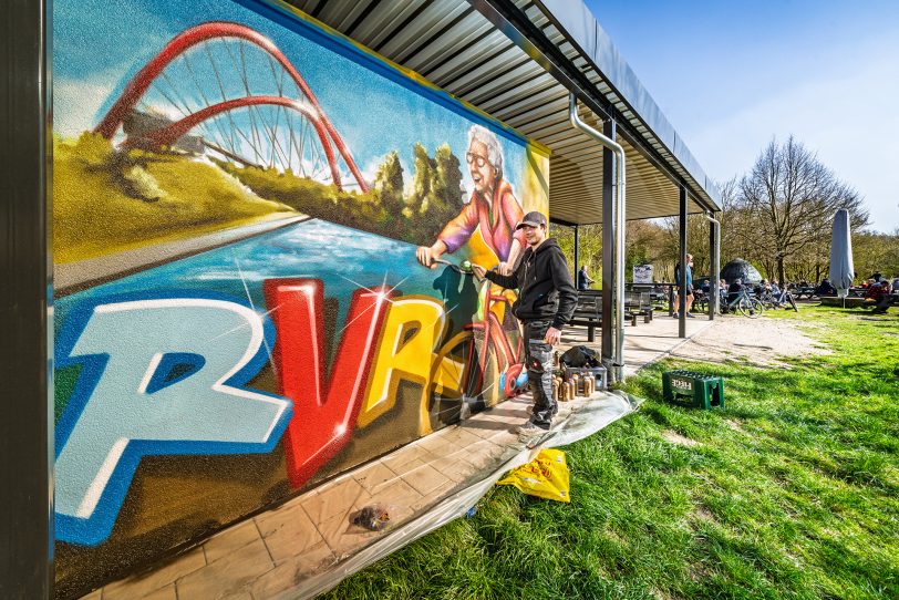 Der Regionalverband Ruhr (RVR) hat den Fahrrad-Rastplatz an der Erzbahntrasse Anfang April 2025 in Betrieb genommen. Die Außenwände hat der Gelsenkirchener Graffiti-Künstler Beni Veltum mit Motiven aus der Region verziert.