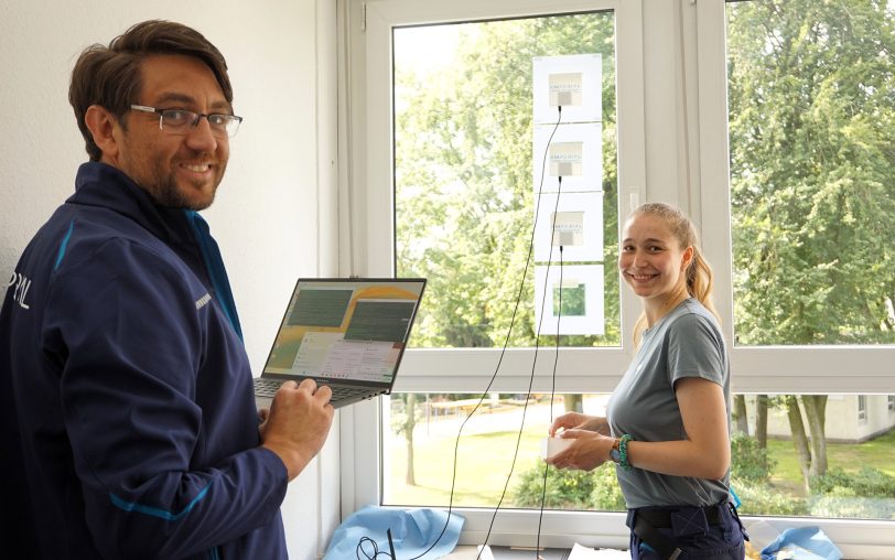 Die Amperial-Mitgründer Niall Killilea (CTO, links) und Katja Wadlinger (Head of R&D) richten bei den Stadtwerken Herne die Testreihe ein: Das Unternehmen hat eine innovative Fensterfolie zur Gebäudekühlung entwickelt.