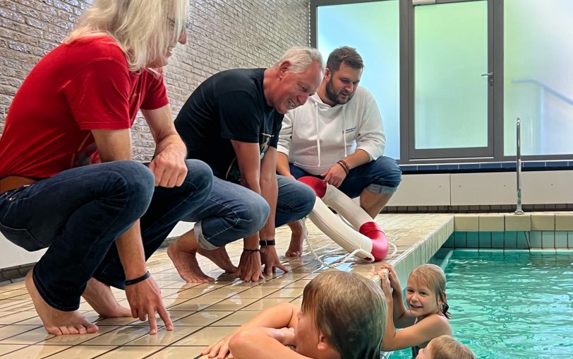 Die Spender der Schwimmgutscheine (v.li.) Horst Schröder (Mondritter), Frank Tocholski (Mondritter) und Moritz Trepper (Filialleiter Herne Sparda-Bank West eG) quatschen mit den Kindern im Wasser.