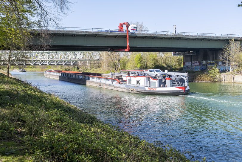 Der Kranwagen steht auf der Brücke und schwenkt den Ausleger mit Korb nach unten.