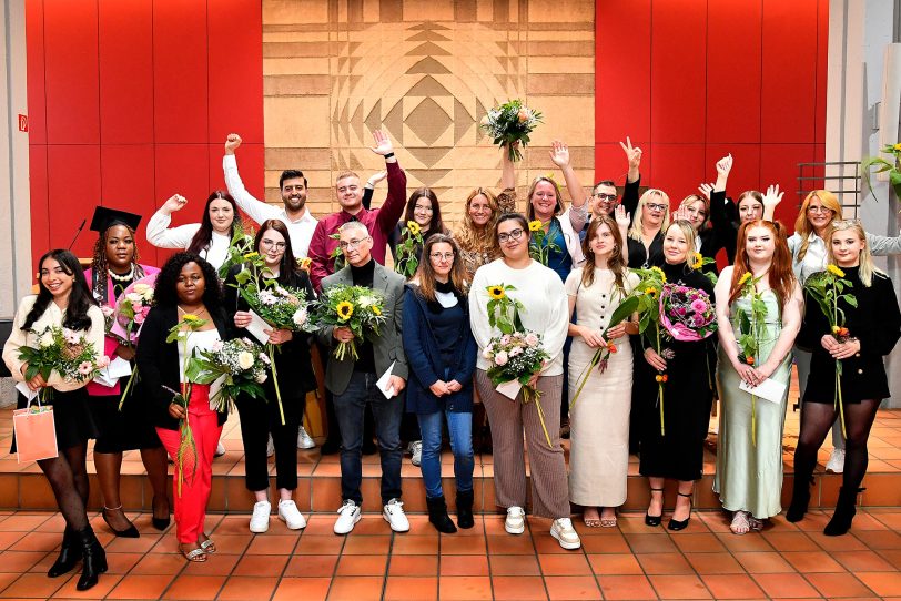 21 frisch examinierten Pflegefachkräfte stellen sich mit ihren Kursleitungen zum Gruppenfoto.