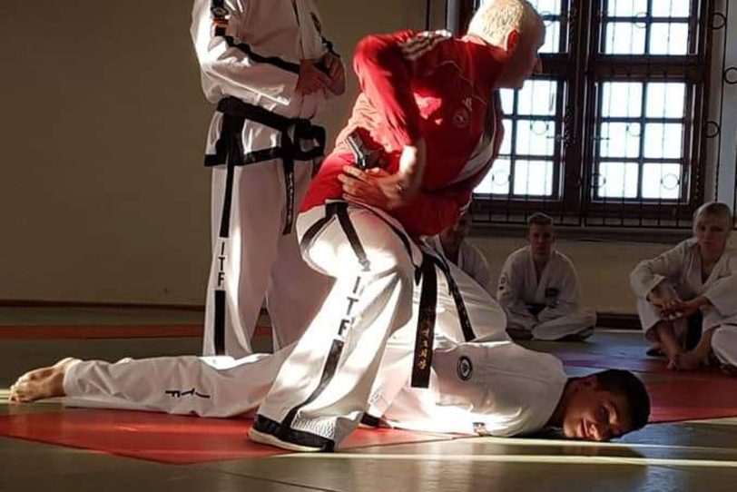 Master Nycek (rote Jacke) stehend über Pascal Latusek (TKD-Wanne) nach Abwehr.