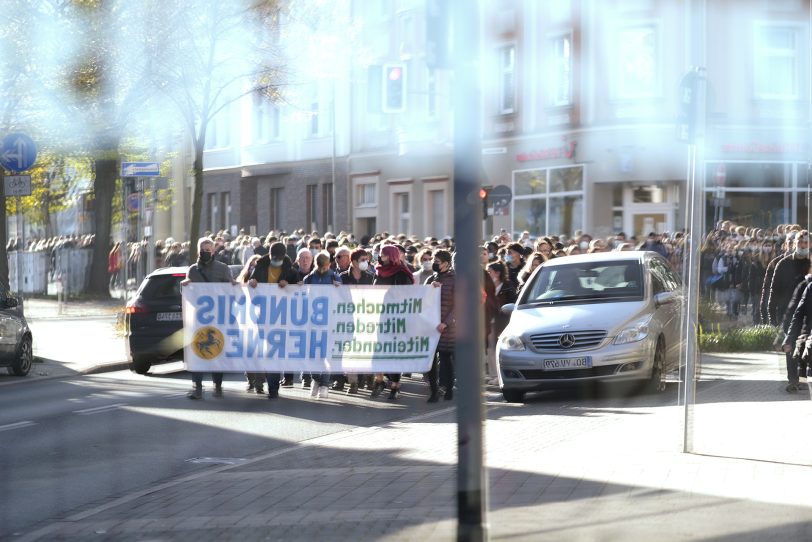 Gedenken an die Judenverfolgung und die Opfer in der Reichsprogromnacht 1938 in Herne (NW), am Dienstag (09.11.2021). Der Zug der Teilnehmer der Gedenkveranstaltung vom Shoah-Mahnmal am Kulturzentrum zum Mahnmal an der Bebelstraße spiegelt sich in einer Schaufensterscheibe.