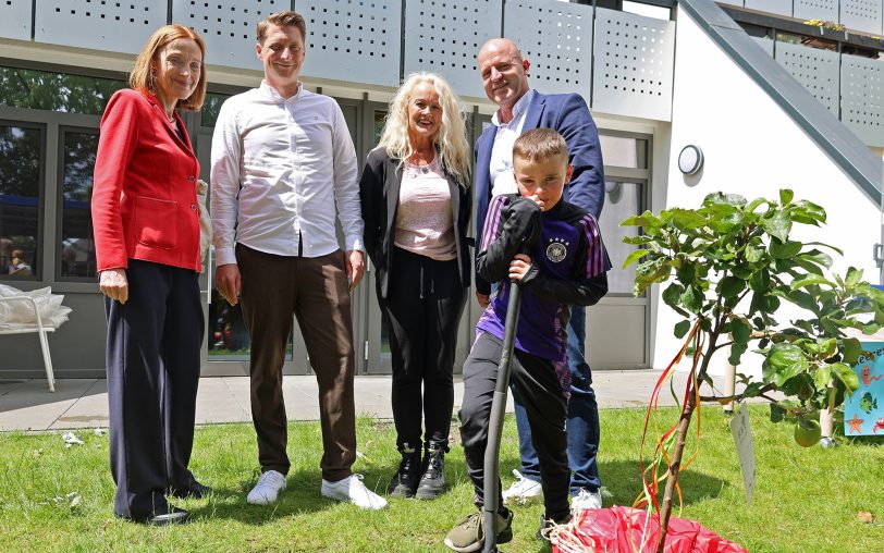 Der junge Liam packt tatkräftig mit an, damit (v.li.) Sabine Bittner, stellvertretende Jugendamtsleiterin der Stadt Herne, Geschäftsbereichsleitung Tobias Rahe, Kita-Leiterin Kerstin Guth und Regional-Geschäftsführer Diakon André Weber den neuen Zwerg-Apfelbaum im Garten der Kita „Wittekindshofer Wichtel“ auch ordentlich einpflanzen.