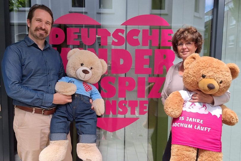 Angelika Li Pira als Schatzmeisterin des Vereins „Aktiv gegen Brustkrebs Bochum“ und Maskottchen Help trafen sich zur symbolischen Spendenübergabe mit Malte Schmidt von den Deutschen Kinderhospiz Diensten und Bärenbotschafter Hope an den Claudius-Höfen in Bochum.