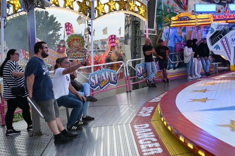 Besucher der Cranger Kirmes am Rundfahrbetrieb Shake and Roll Riesenrad Jupiter, Kettenkarussel Wellenflug Blick auf die Cranger Kirmes von der Rathausstraße aus. Im Bild Riesenrad Jupiter, Hochfahrbetrieb Evolution sowie der Turm vom Hochfahrbetrieb Hangover The Tower