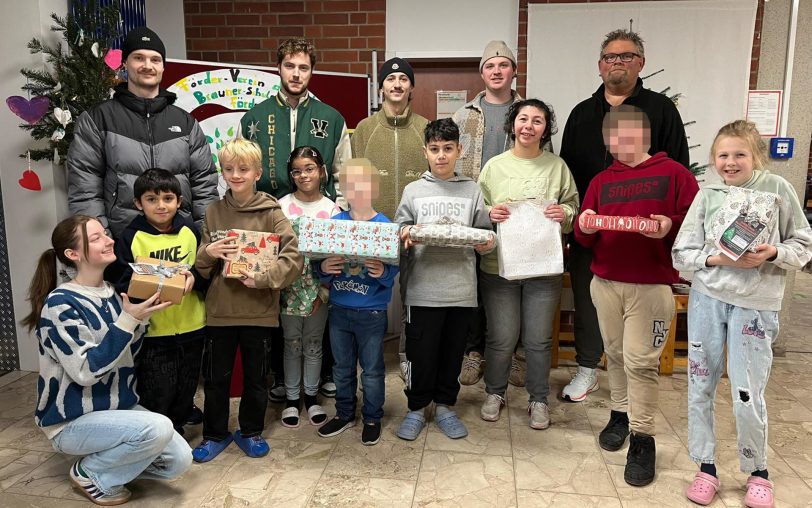 Der Herner EV um Coach Dirk Schmitz (hinten, re.) überbrachte die Geschenke der Wunschbaumaktion für Kinder der Robert-Brauner-Schule.