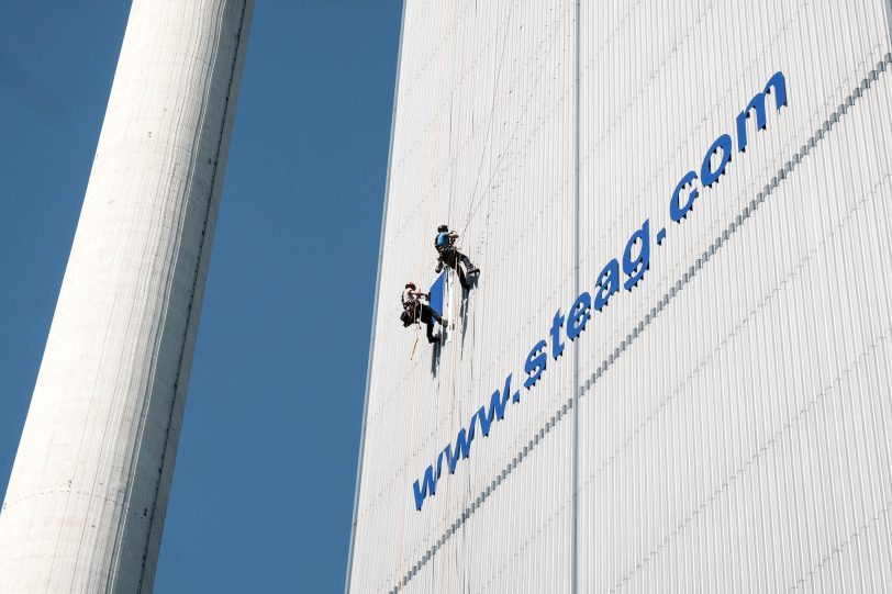 Industriekletterer bringen am Kesselhaus Block 4 der Steag AG in Baukau eine Werbetafel an.