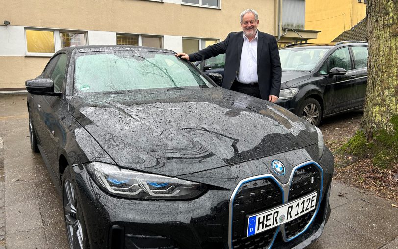 Er ist der Chauffeur von OB Dr. Frank Dudda: Domenico Nimi neben seinem Dienstwagen, ein BMW i4.