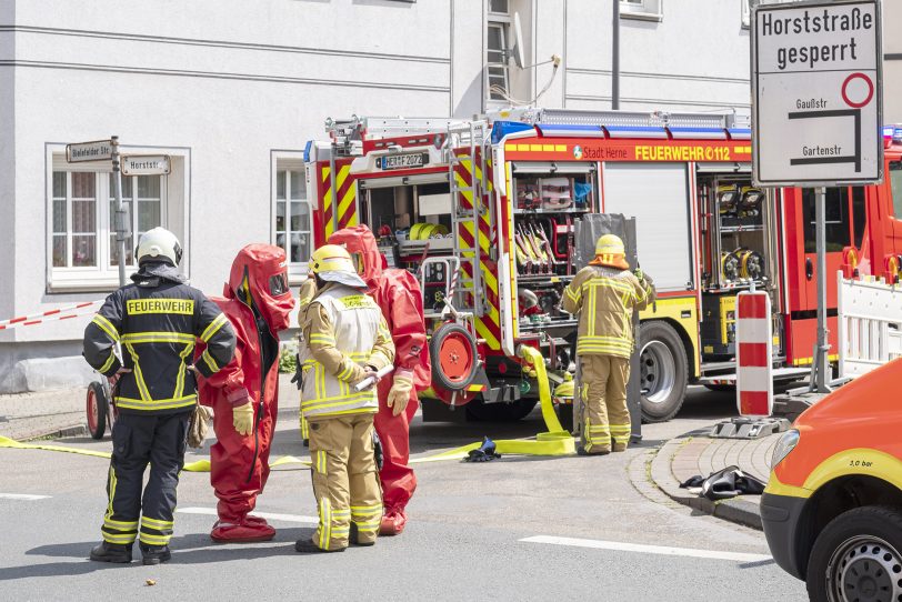 Feuerwehrleute in Chemikalienschutzanzügen stehen zum Einsatz bereit.