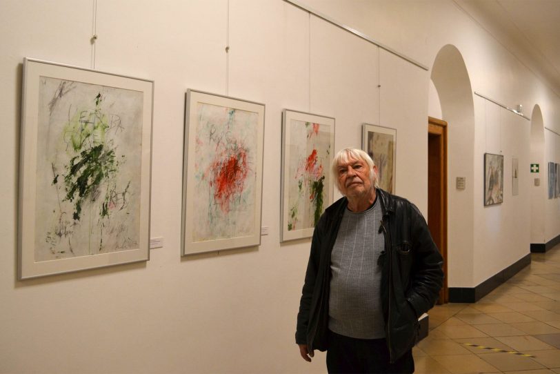 Hans-Jürgen Jaworski im Erdgeschoss des Herner Rathauses vor einer Bildserie zu Martin Luthers Tischreden.