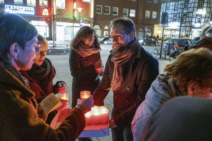 Der evangelische Pfarrer Cornelius Heering verteilt beim ökumenischen Friedensgebet an der Kreuzkirche Kerzen.