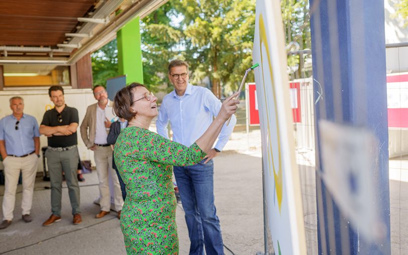 Schulleiterin Gabriele Schlemminger (vorne) griff für das Kunstwerk zum Pinsel anstelle eines Spatenstichs. Im Hintergrund (v.li.) Bezirksbürgermeister Arnold Plickert, Kämmerer Marc Alexander Ulrich, Stadtsprecher Tobias Kindel und HSM-Chef Christian Keller.