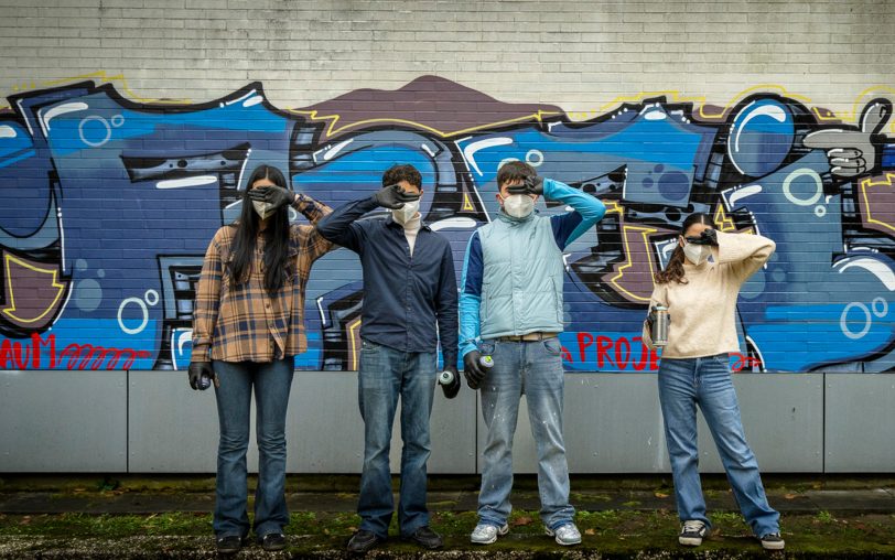 Vier Jugendliche vor dem fertigen Graffiti.