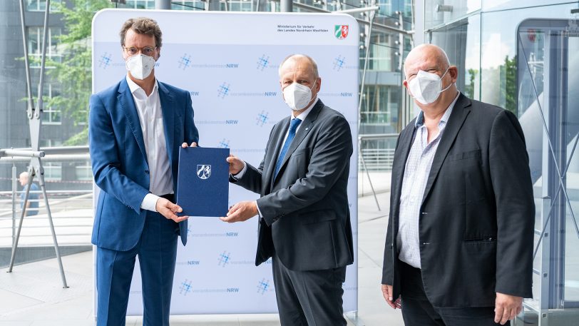 NRW-Verkehrsminister Hendrik Wüst (li.) übergibt den Förderbescheid an HCR-Geschäftsführer Karsten Krüger, MdL Thomas Nückel (FDP, re.) war mit dabei.