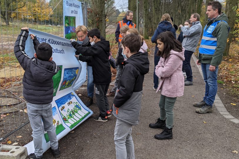 Baustellengalerie Ostbach: Die Schüler hängen die Plakate am Bauzaun entlang des Otto-Hahn-Gymnasiums auf.