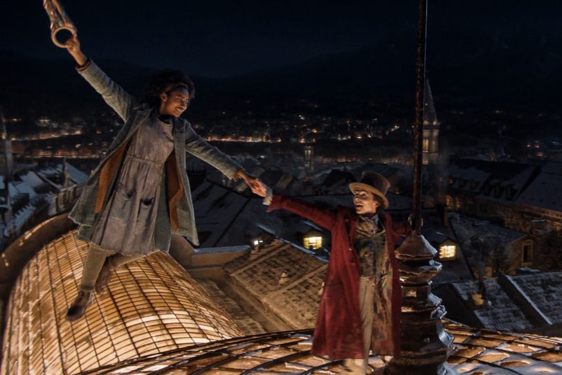 Auf dem Art-Deco-Glaspalast der Galeries Gourmet tanzen das Waisenmädchen Noodle (Calah Lane) und Willy Wonka (Timothée Chalamet).