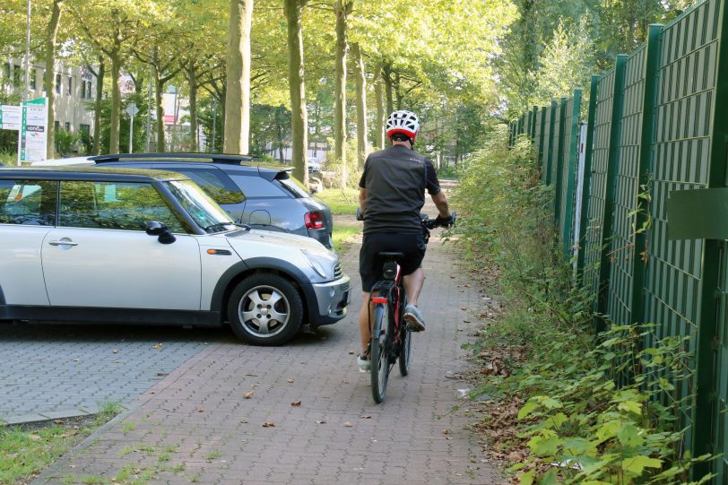 Radtour durch Herne. Wolfgang Neige schlängelt sich zwischen Unkraut und geparkten Autos durch.