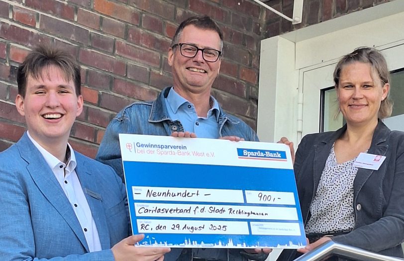 Mika Gertenbach (links), Auszubildender bei der Sparda-Bank West, überreicht einen symbolischen Scheck an Vorstand Christoph Kortenjann und Koordinatorin Gemeindecaritas, Annika Steingräbe, des Caritasverbands für die Stadt Recklinghausen e.V.