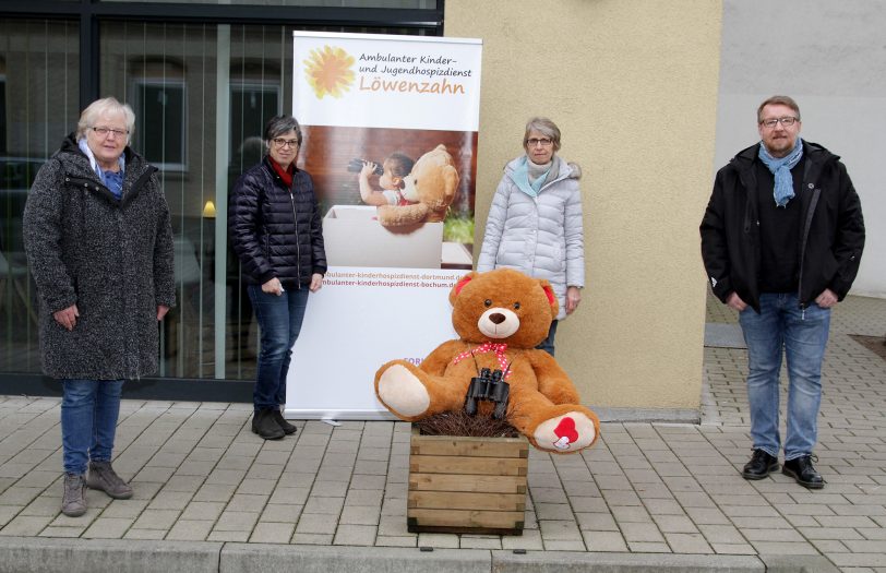 Antje Stark (l.), Vorsitzende der MAV Pflege, und Stephan Stein, Vorsitzender der MAV Wohnen, übergeben einen Teil der Mitarbeitendenspende an (Mitte v.l.) Irene Steiner und Koordinatorin Birgit Schiereck vom Ambulanten Kinder- und Jugendhospizdienst Löwenzahn. Der Bär als Maskottchen ist auch dabei.