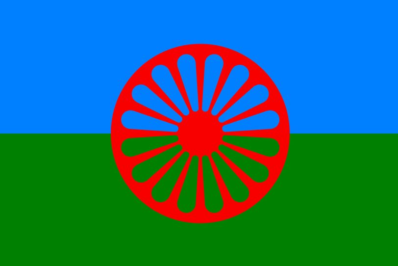 Die Roma-Flagge: Blau steht für den Himmel, grün für die Erde – ein Ausdruck der Naturverbundenheit der Roma. Das als Chakra erkennbare Rad verweist auf die indische Herkunft.