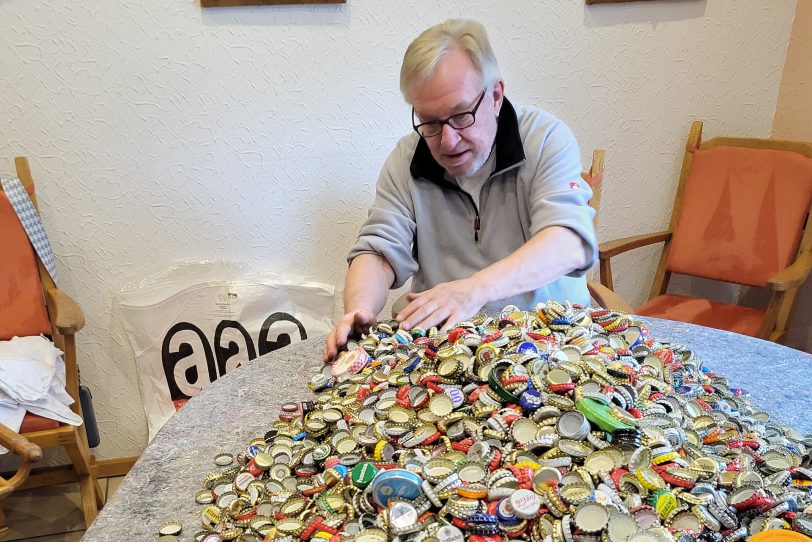 Detlef Brune sitzt vor den Unmengen an Kronkorken.