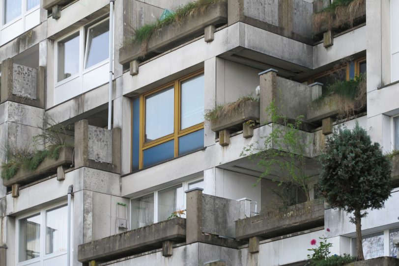 Terrassenwohnhaus Girondelle - Liebloser Bauunterhalt: Das bauzeitliche Farbkonzept mit kräftigen ockerfarbenen Fensterrahmen mit azurblauen Panelen ist. durch unpassenden Fensterersatz heute nur noch in Teilen vorhanden.