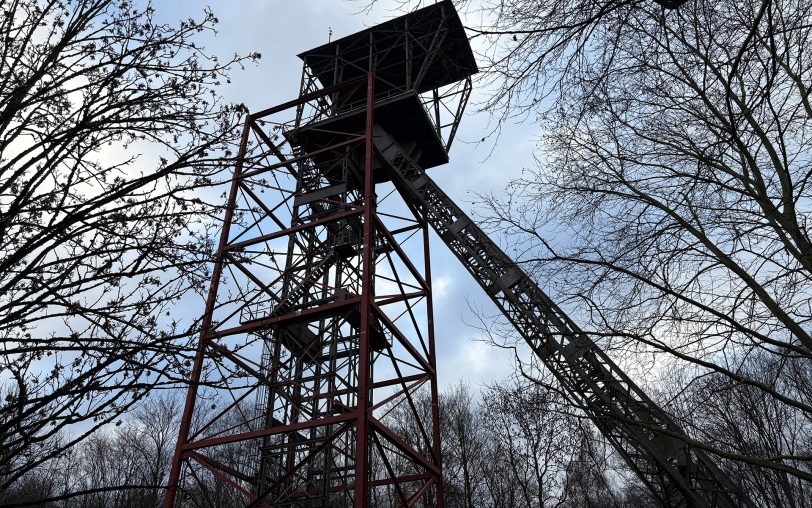 Die Sanierung des Fördergerüsts Teutoburgia beginnt. Dafür wurde ein rotes Stahlkorsett errichtet, damit ein Arbeitsgerüst aufgestellt werden kann und Halt hat.