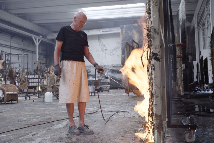 Anselm Kiefer flämmt ein Materialbild in seinem gewaltig dimensionierten Atelier in Croissy.