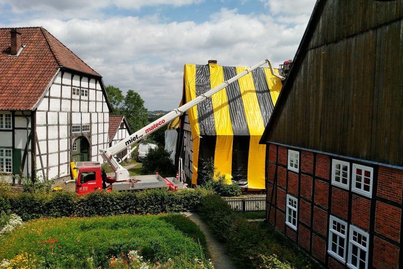 Blick aus Richtung des Gartens am Valepagenhof auf das Haus Stahl, das gerade in die farbigen Folien gehüllt wird.