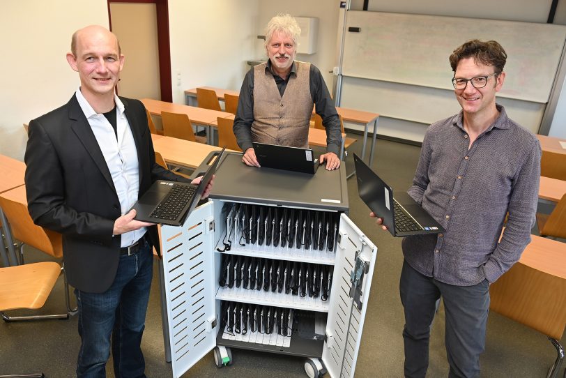 Das Projektteam (v.l.) Prof. Dr. Lutz Niehüser, Prof. Dr. Ralf Beck. Und Prof. Dr. Marcel Hoffmann stehen vor einem der fünf Laptopschränke mit Ladefunktion.